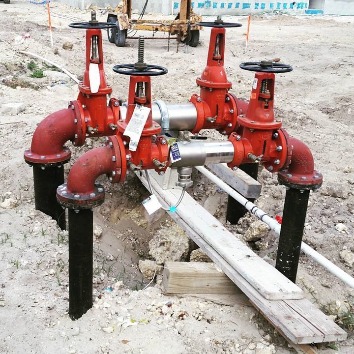 A bunch of red pipes are sitting in the dirt