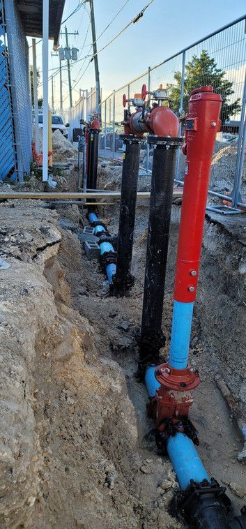 A red and blue fire hydrant is sitting in the dirt next to a fence.