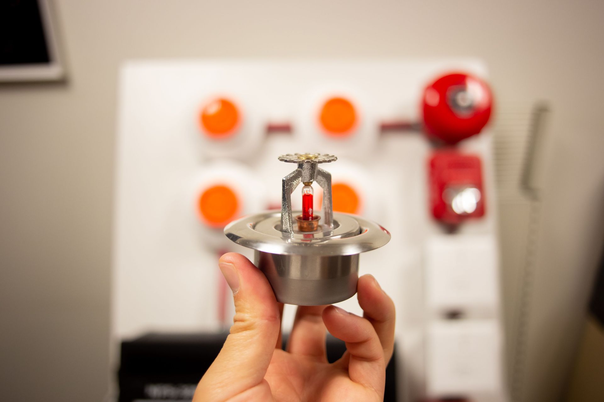 A person is holding a fire sprinkler in their hand.