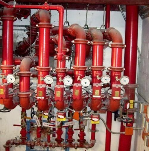 A bunch of red pipes with clocks on them