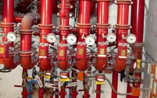 A bunch of red pipes with gauges attached to them