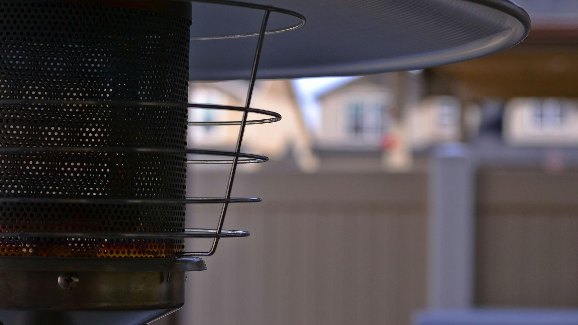 A close up of a patio heater with a house in the background