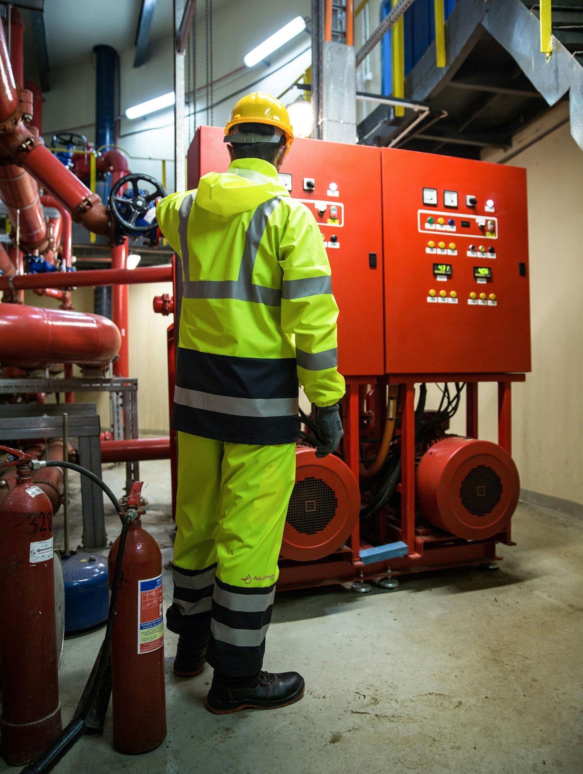 A man in a yellow safety suit is working on a machine