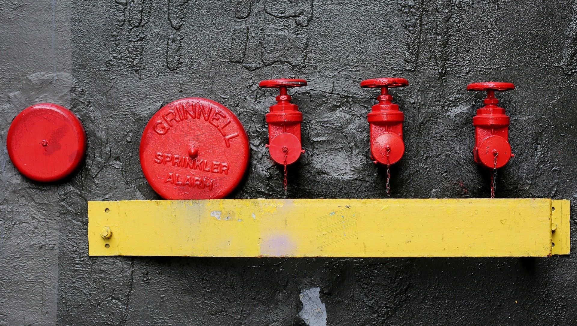 A row of red fire hydrants are lined up on a yellow shelf