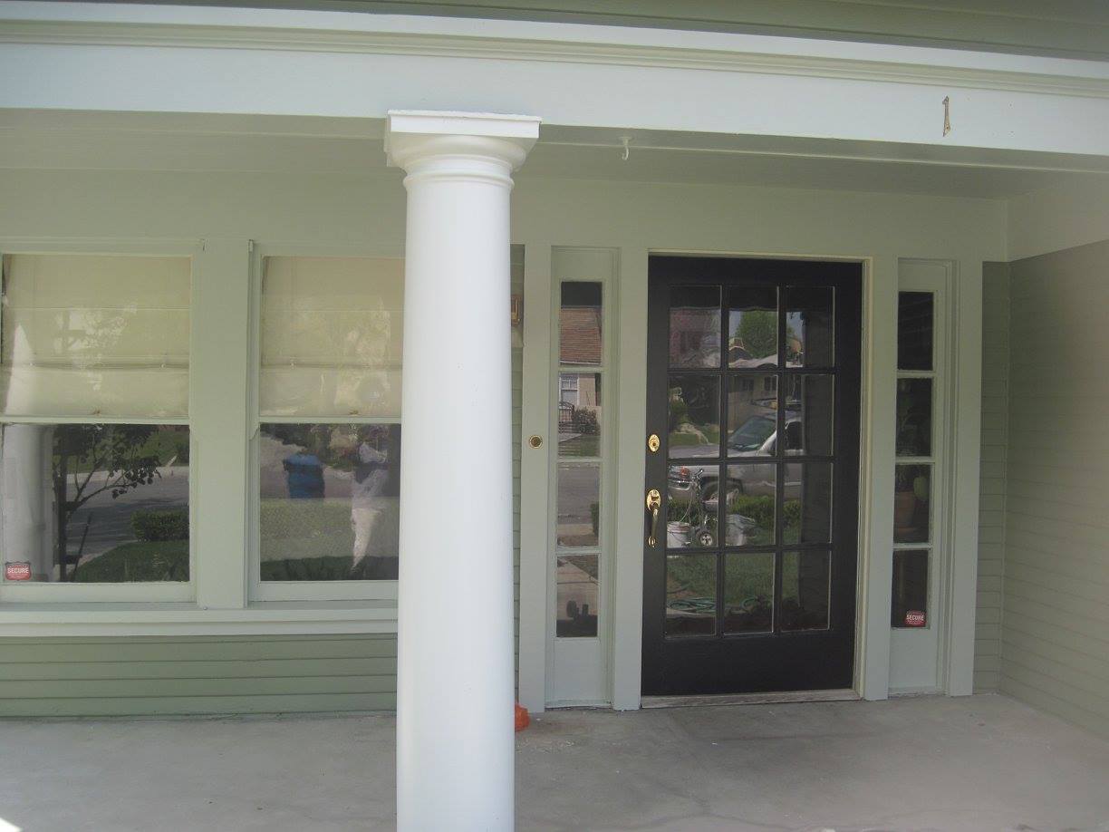 A porch with a black door and a white pillar