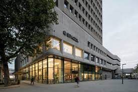 Een hoog gebouw met veel ramen en een boom ervoor.