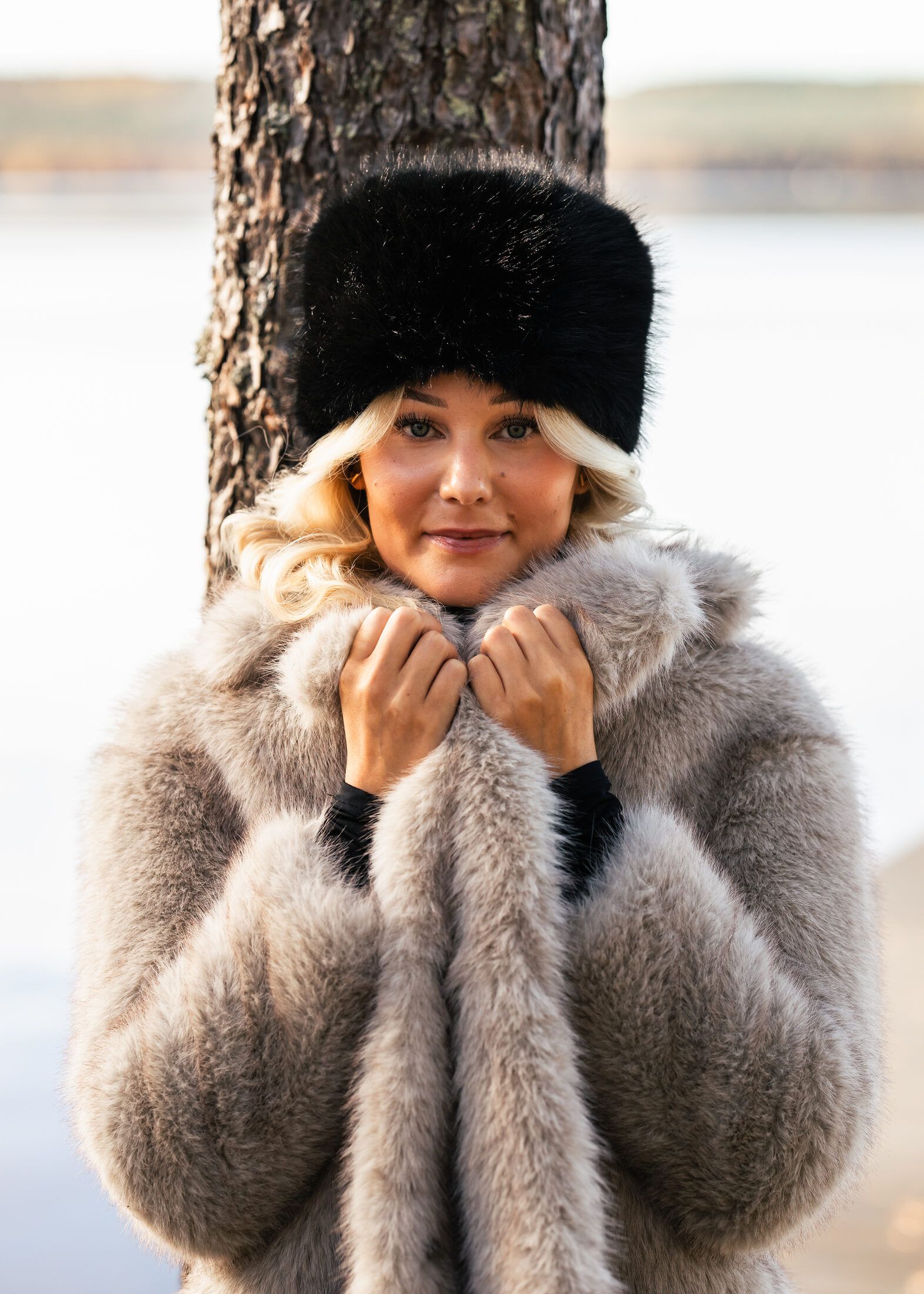 Woman in a fur hat and warm coat by a lake in Lapland