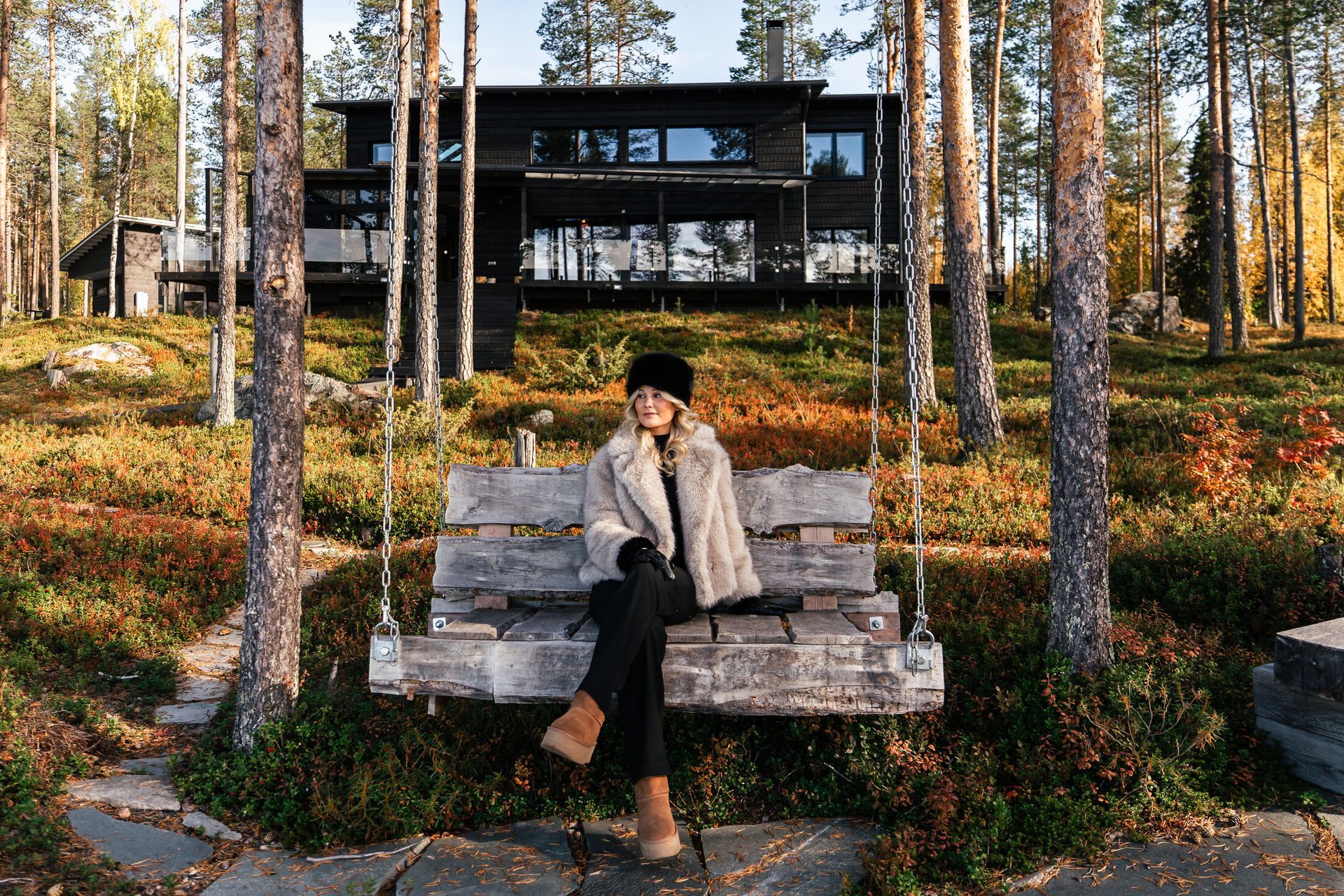 Guest on a wooden swing in front of a lakeside home in autumn