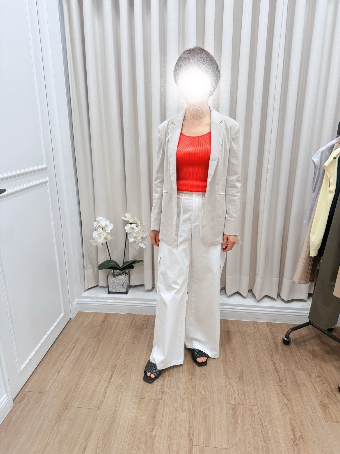 一位身穿運動夾克和白色褲子的女士站在房間裡。
