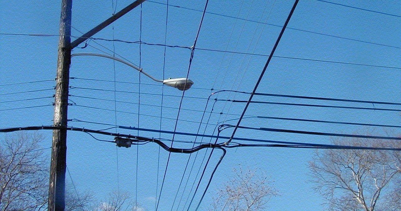 A street light is hanging from a pole surrounded by power lines