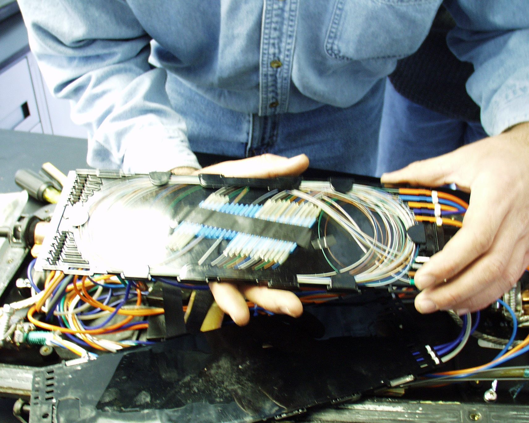 A man in a blue shirt is holding a piece of electronic equipment