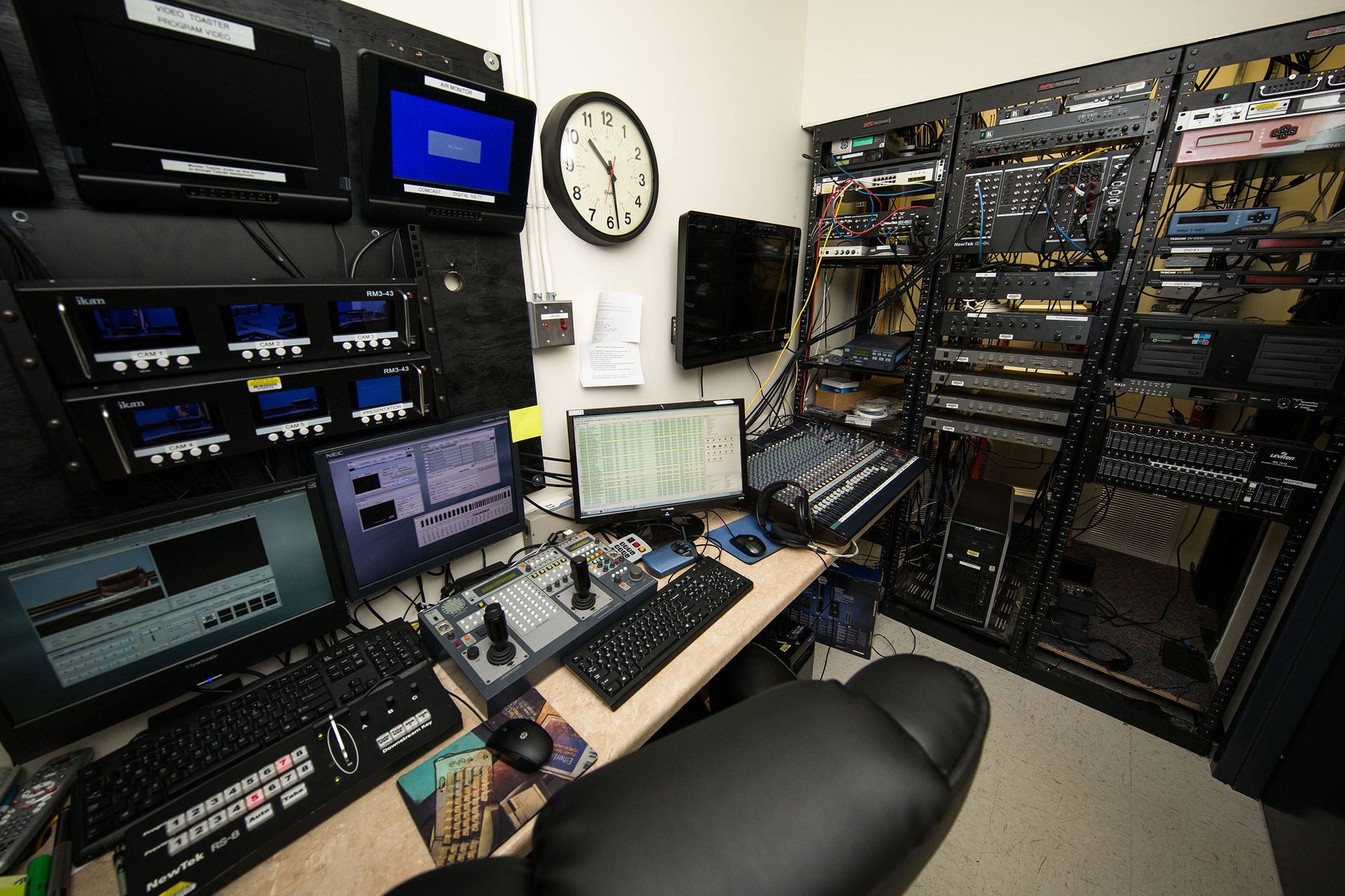 A room with a lot of computer equipment and a clock on the wall