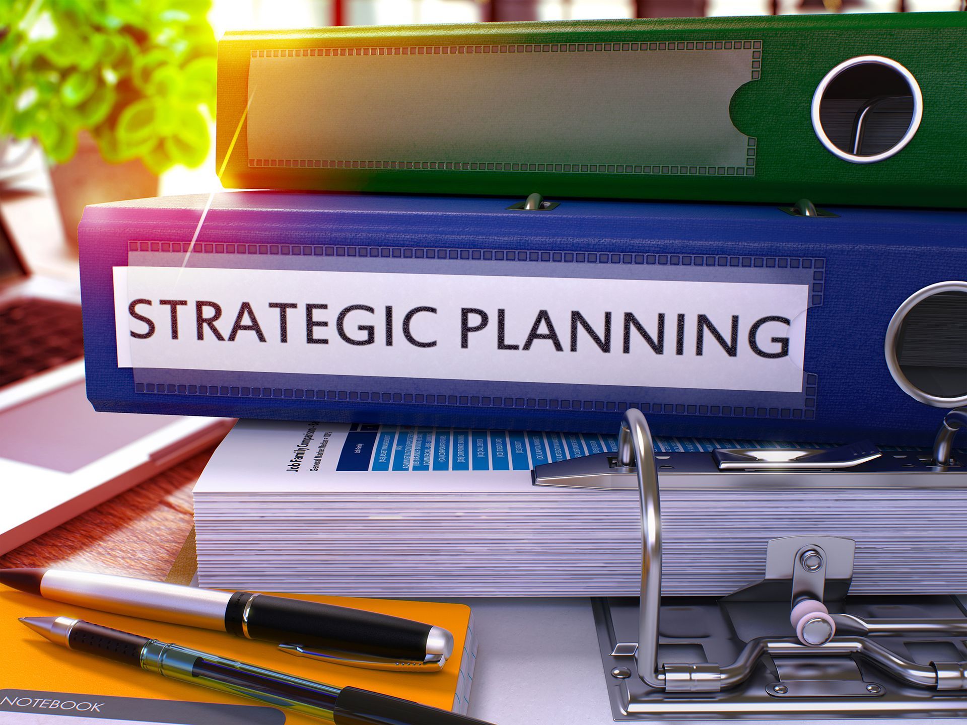 A stack of strategic planning binders sitting on top of each other on a desk.