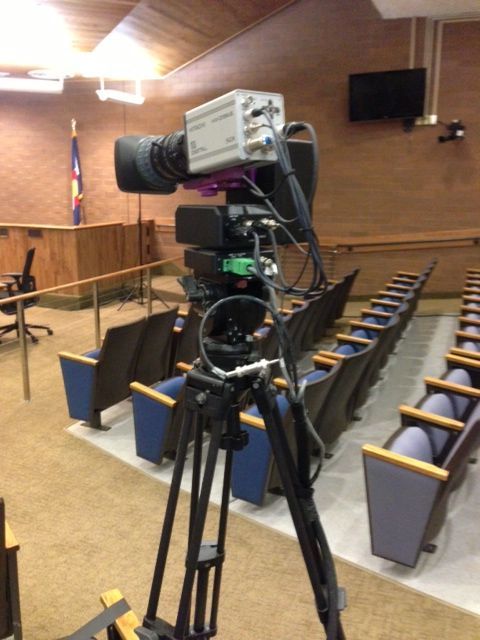 A camera is sitting on a tripod in an auditorium