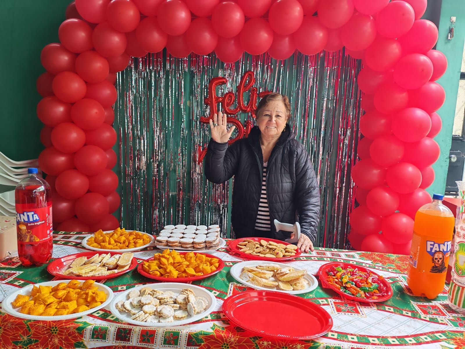 Mujer de pie detrás de una mesa de comida en una exhibición festiva de globos rojos.