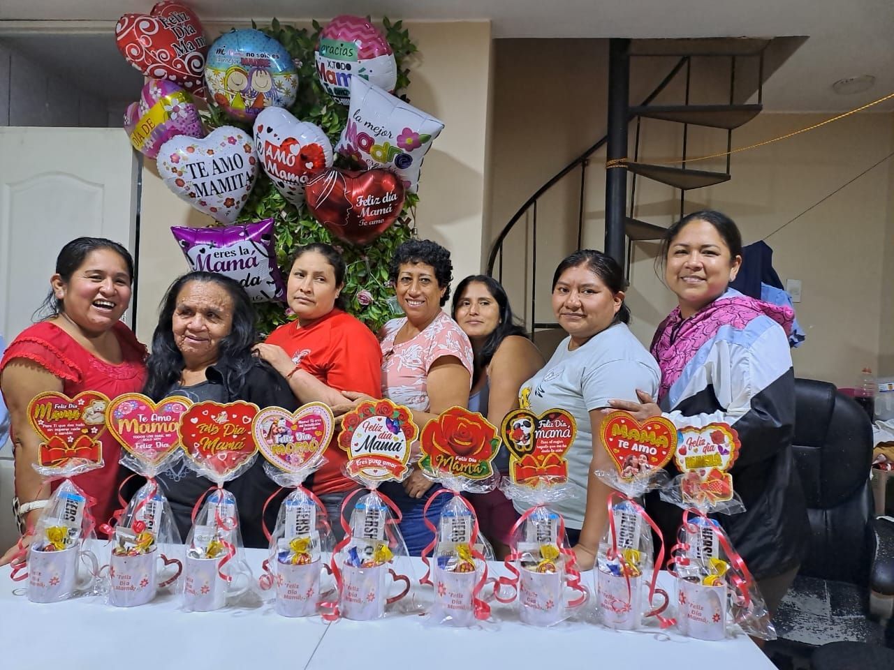 Grupo posando detrás de cestas de regalo de San Valentín y globos en forma de corazón sobre una mesa en una escalera.