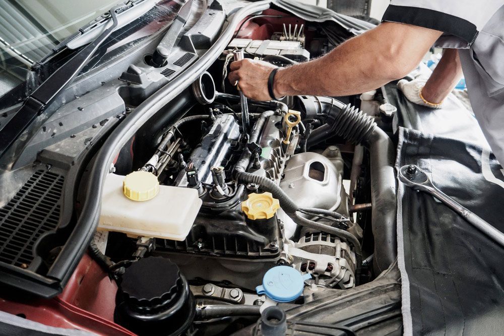 A Man Is Working On The Engine Of A Car — Too Ezy Auto Electrics In Townsville, QLD