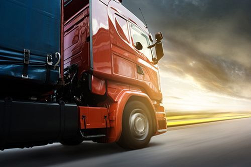 A Red Semi Truck Is Driving Down A Highway At Sunset — Too Ezy Auto Electrics In Townsville, QLD