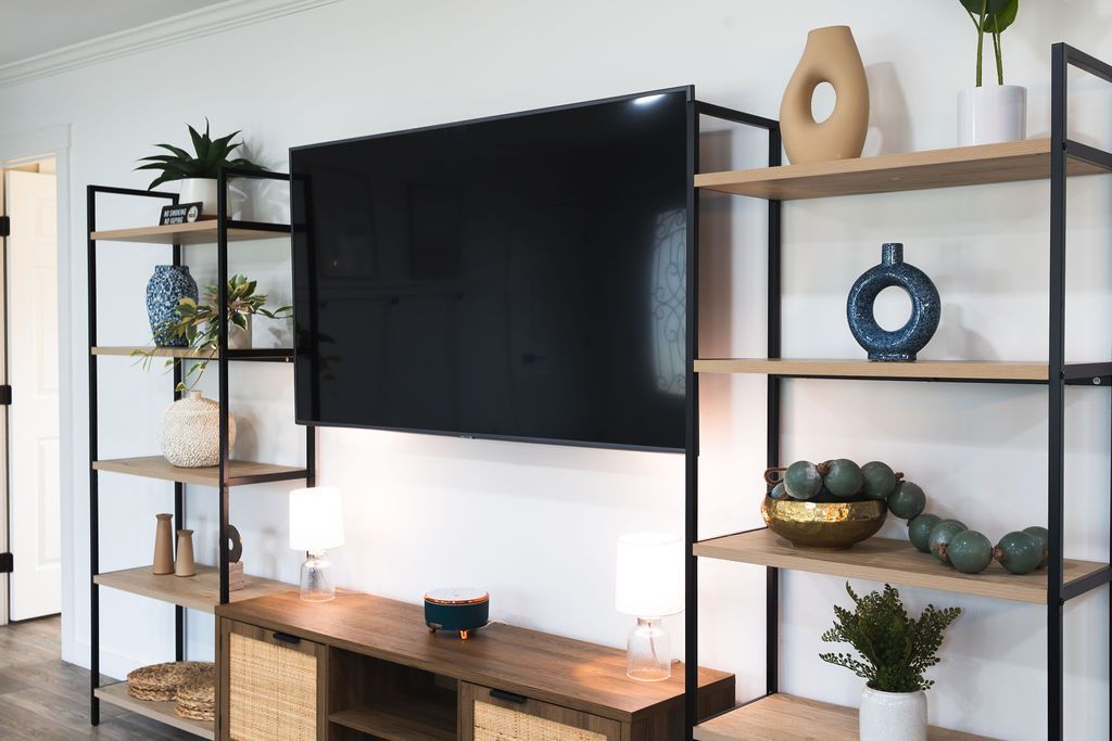 Media console with TV, shelving, and decor; wood, metal, and neutral tones.