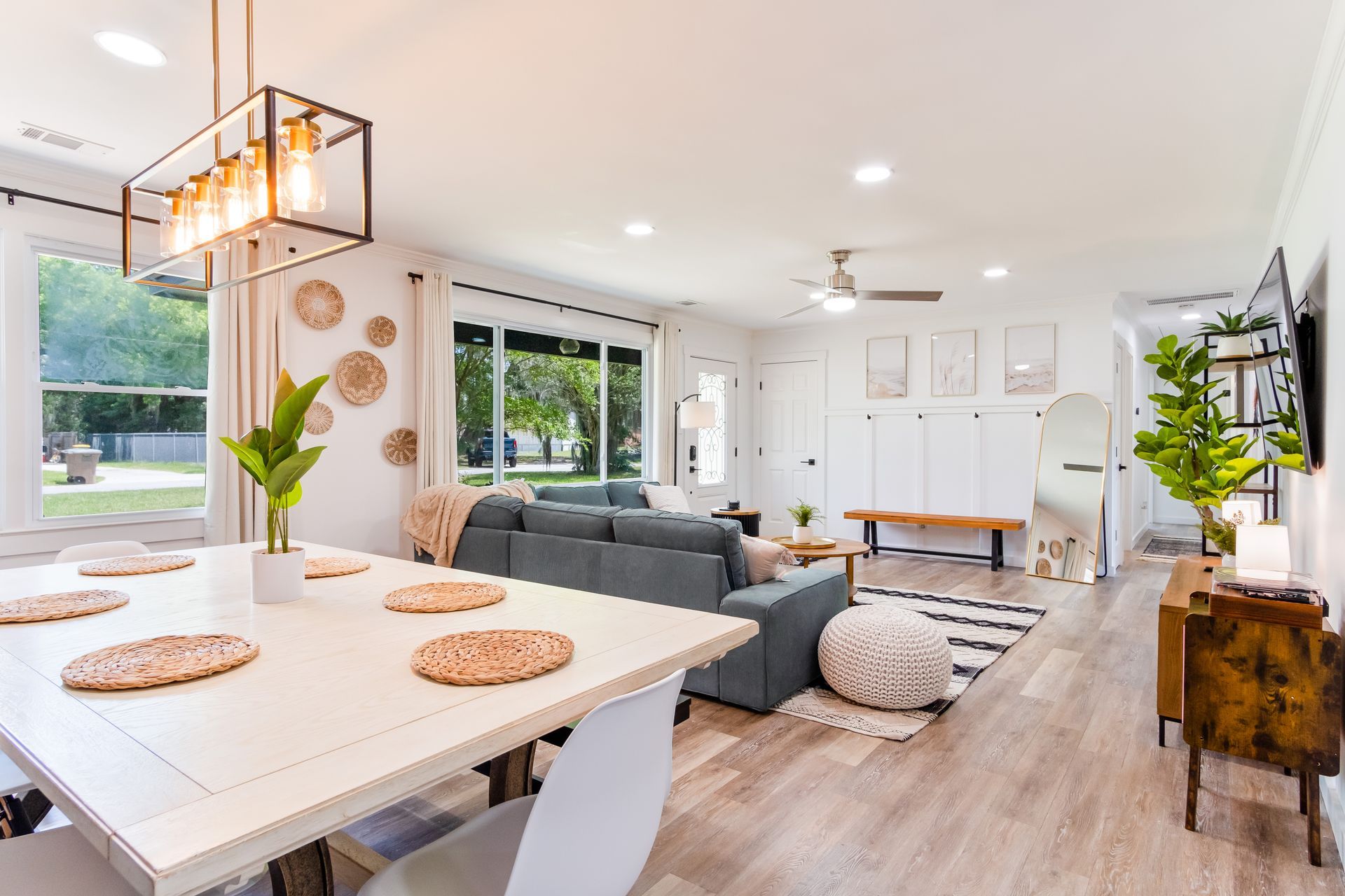 Bright, modern open-concept living space with dining table, sofa, and decorative wall accents.