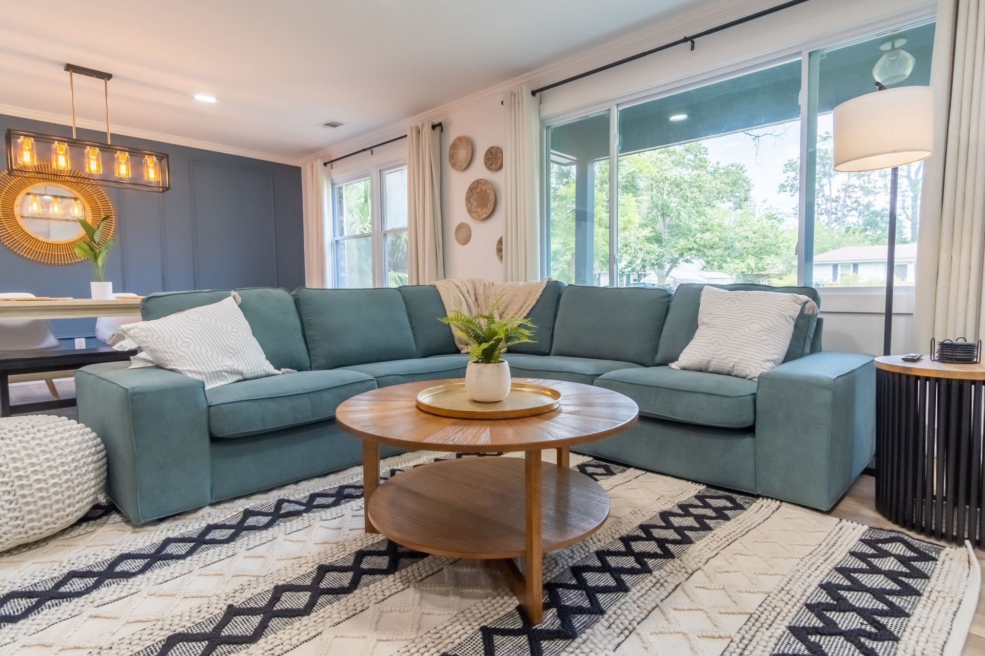 Spacious living room with teal sectional sofa, wooden coffee table, and patterned rug.