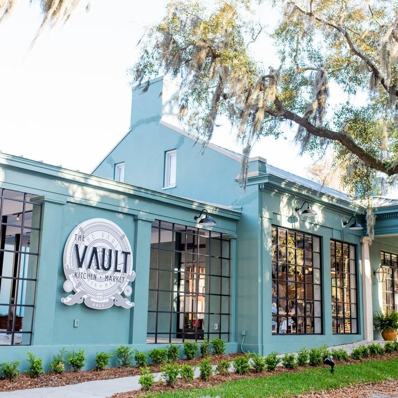Exterior of Vault Kitchen & Market restaurant with teal walls, black-framed windows, and sign.