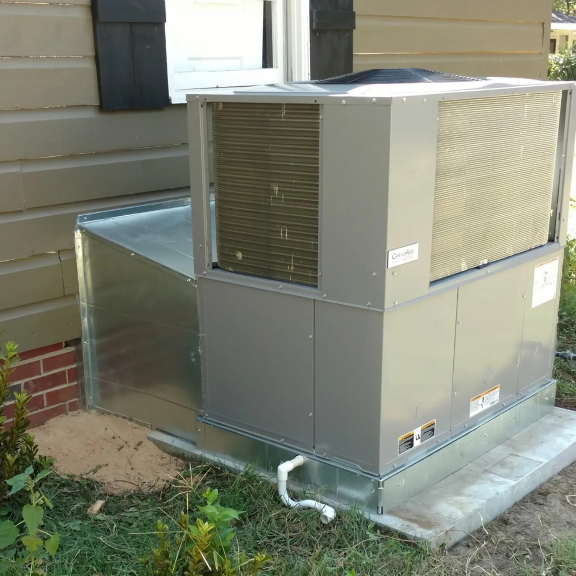 A large air conditioner is sitting outside of a house.