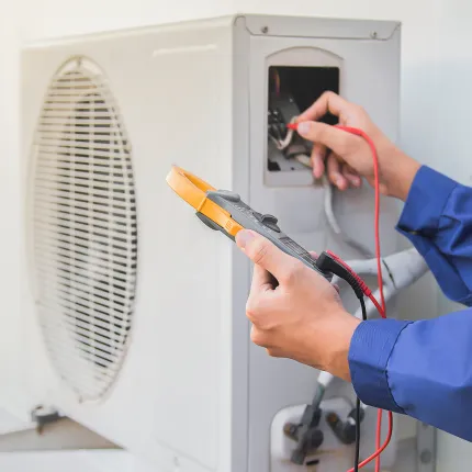 A person is working on an air conditioner with a multimeter.