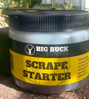 Black jar of Big Buck Adventures Scrape Starter with yellow label and black lid outdoors
