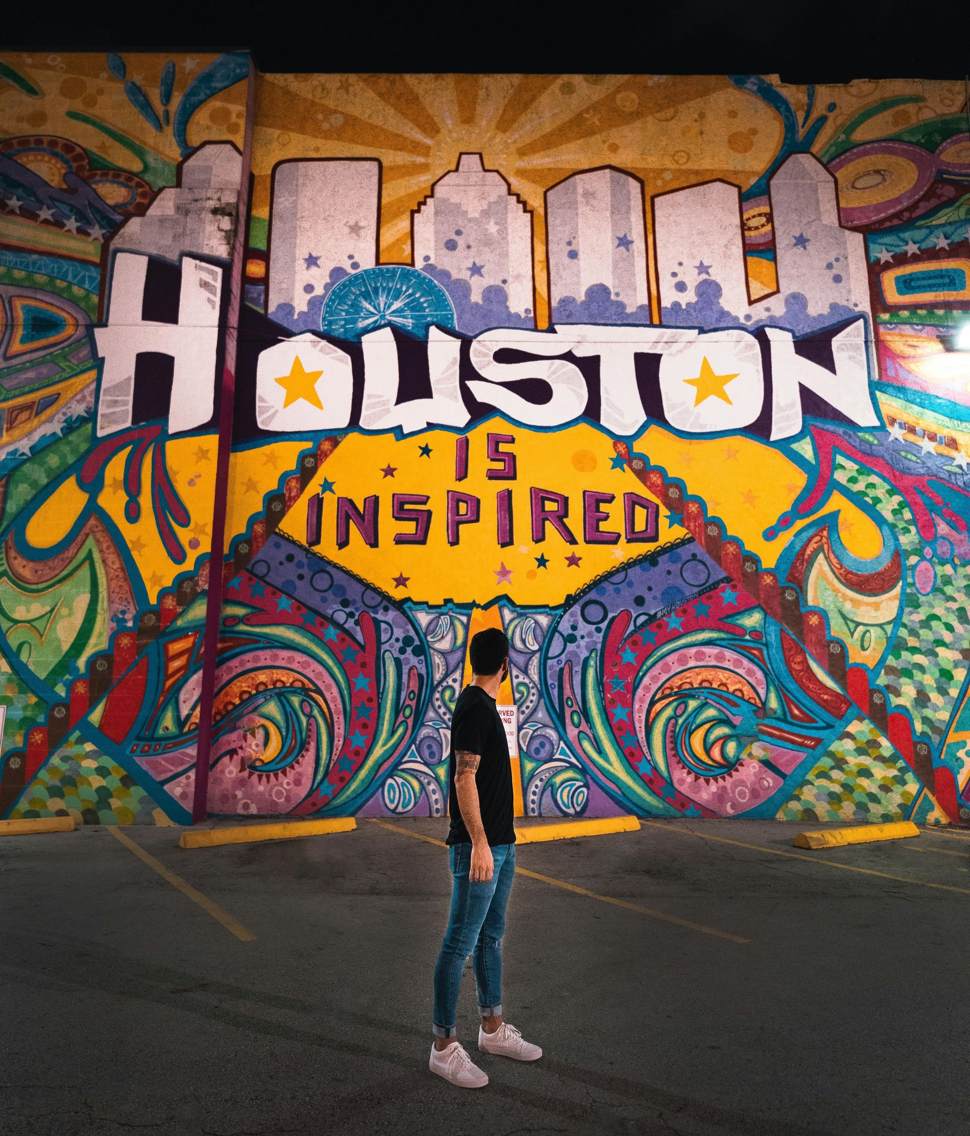 Man stands before a Houston mural,