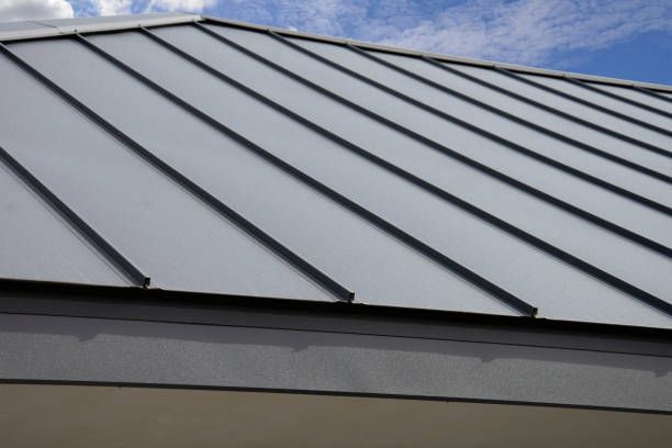 Metal roof with gray panels against a blue sky.