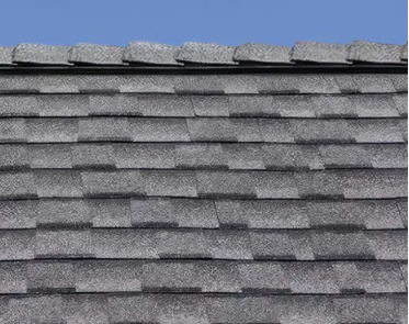 Gray asphalt shingle roof against a blue sky.