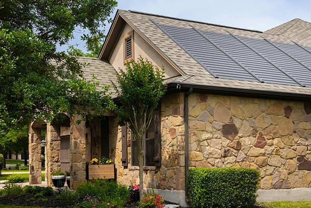 A modern house with solar panels on the roof, sunny day.