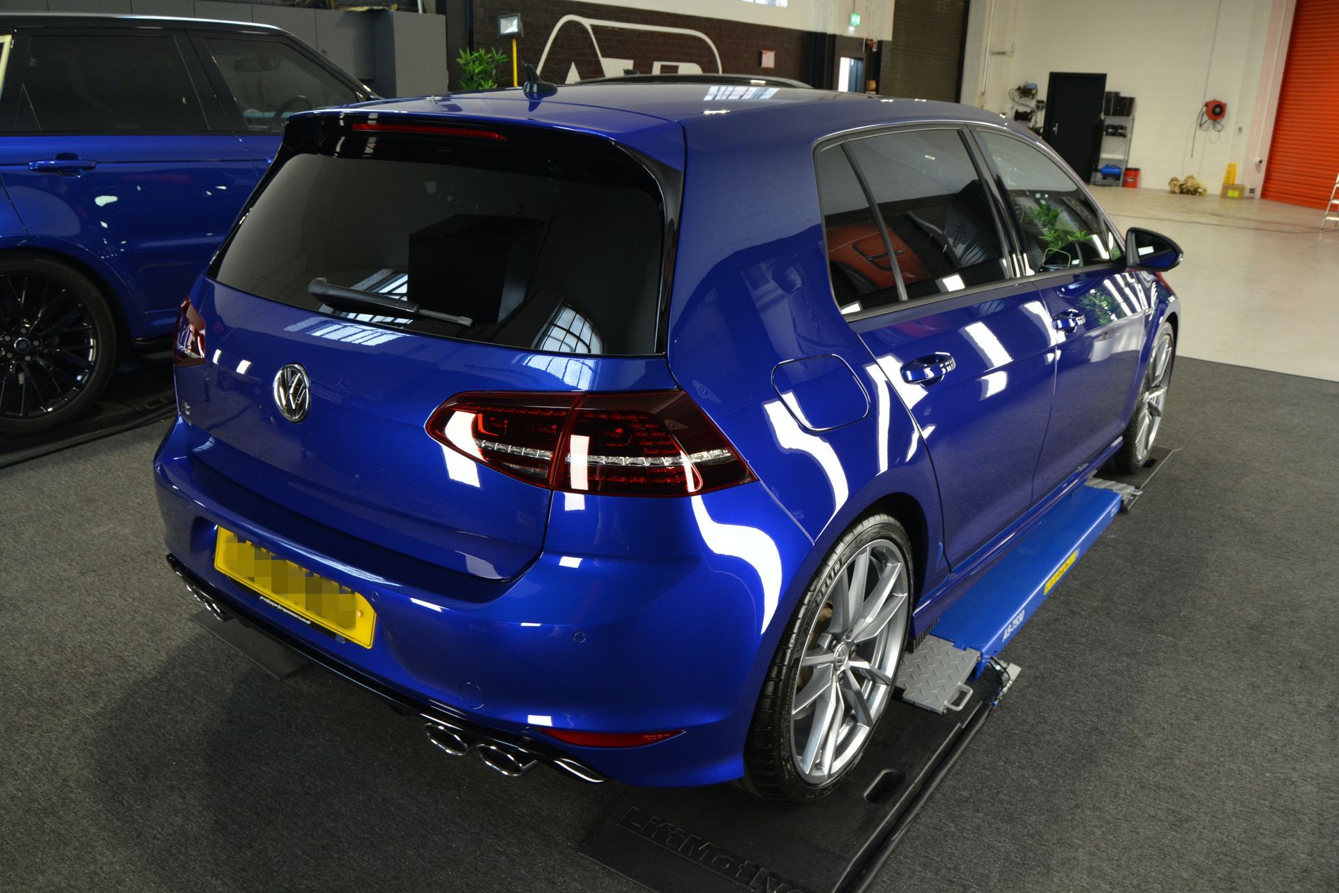 A blue car is sitting on a lift in a garage