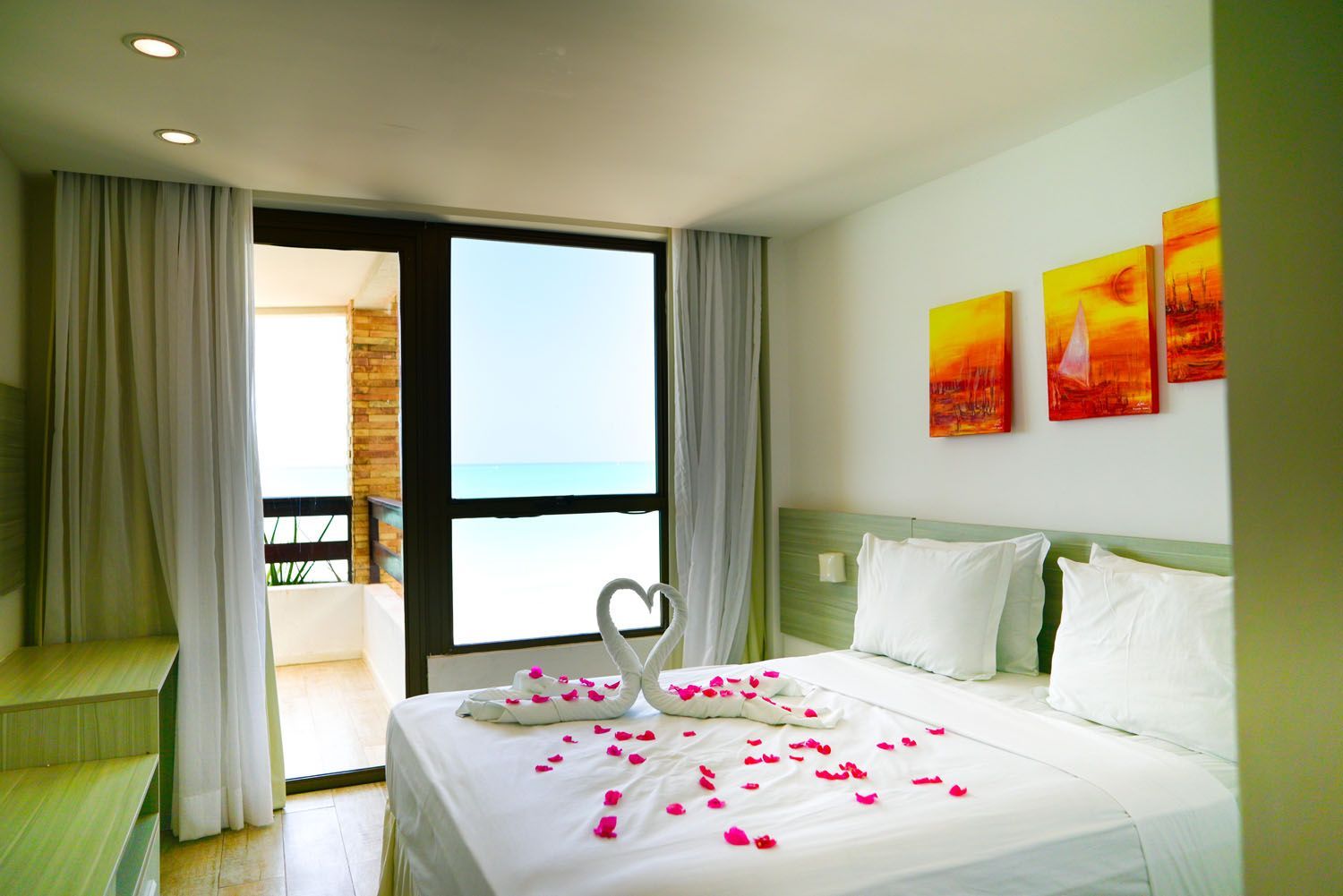 Um quarto de hotel com uma cama grande e varanda com vista para o oceano