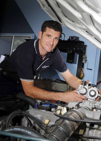 A Man is Working on a Car Engine With the Hood Open