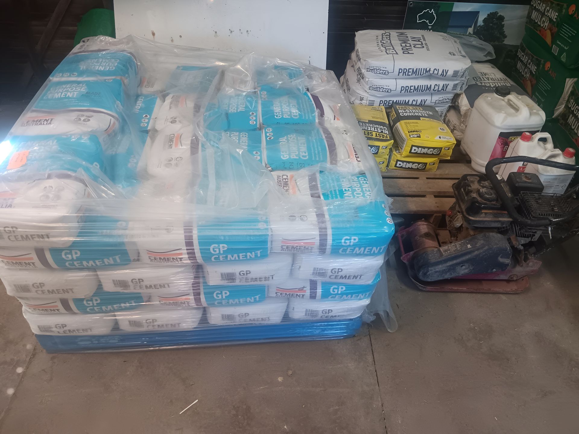 Pallet of Cement Bags Wrapped in Plastic, With Construction Equipment — Laurieton Landscape Supplies In Bonny Hills, NSW