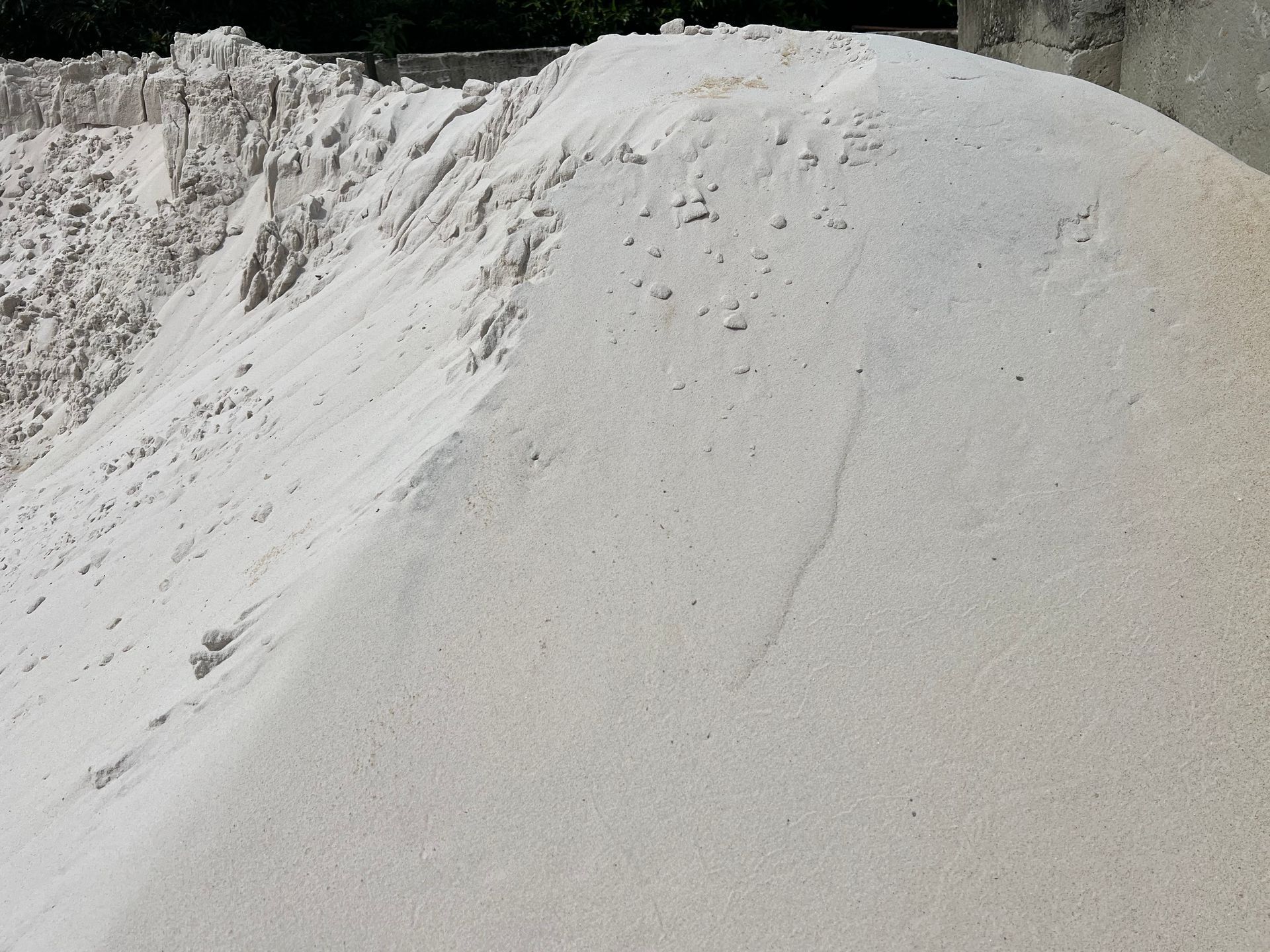 A large, textured pile of fine, light-coloured sand sits against a dark background — Laurieton Landscape Supplies In Kew, NSW
