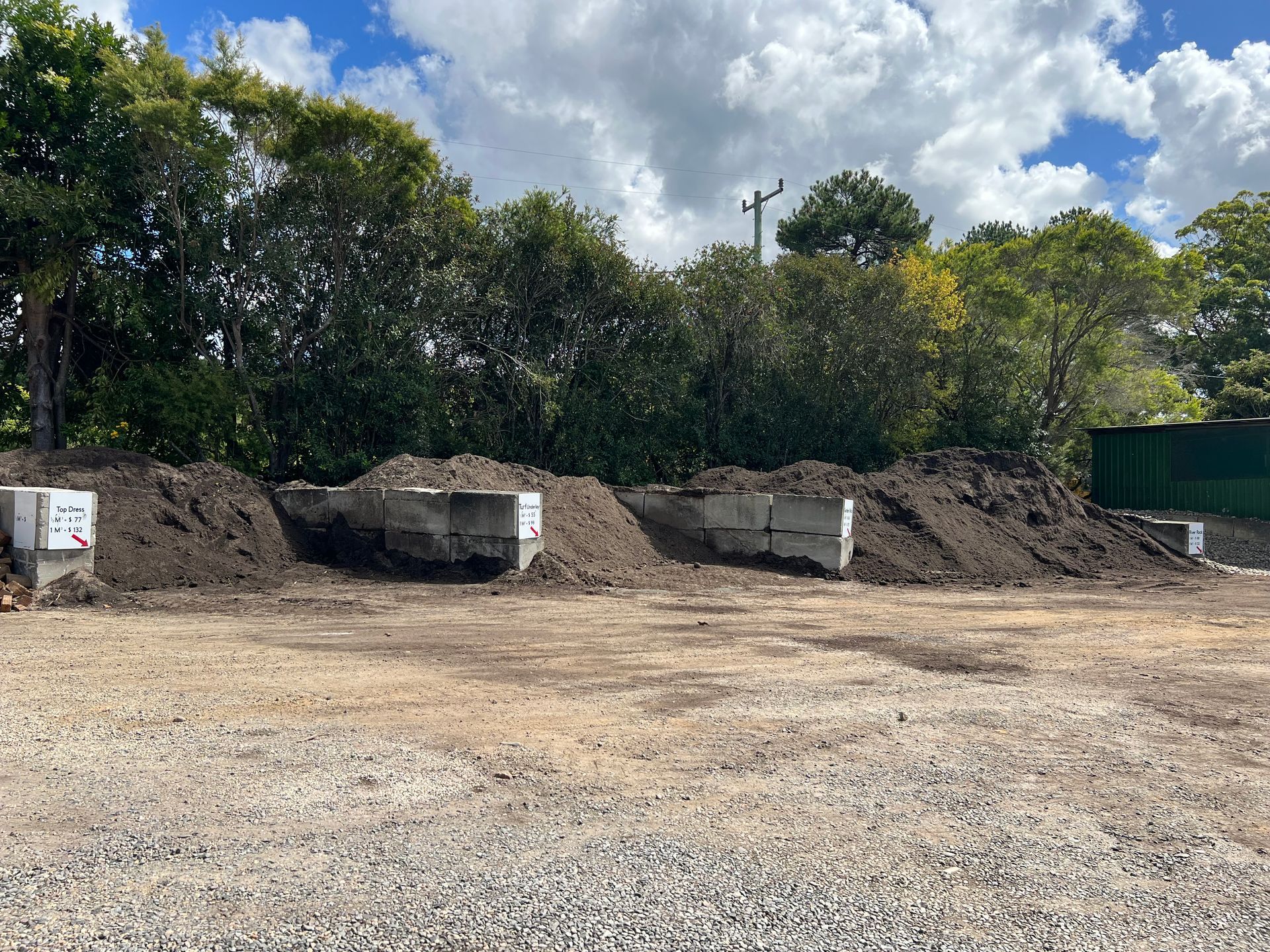 Several large piles of soil contained by concrete blocks — Laurieton Landscape Supplies In Bonny Hills, NSW