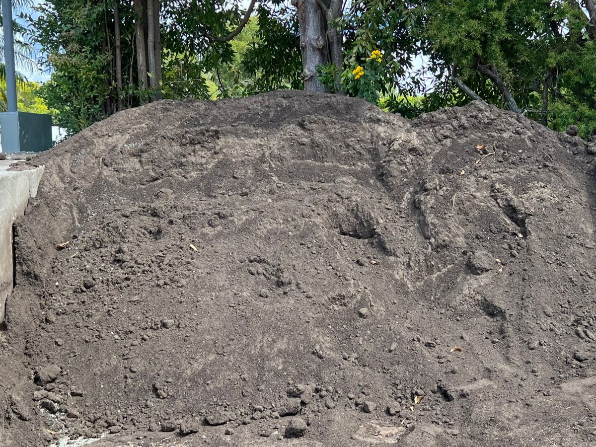 A large, rounded pile of dark brown soil sitting in an outdoor area contained by concrete retaining walls — Laurieton Landscape Supplies In Kew, NSW