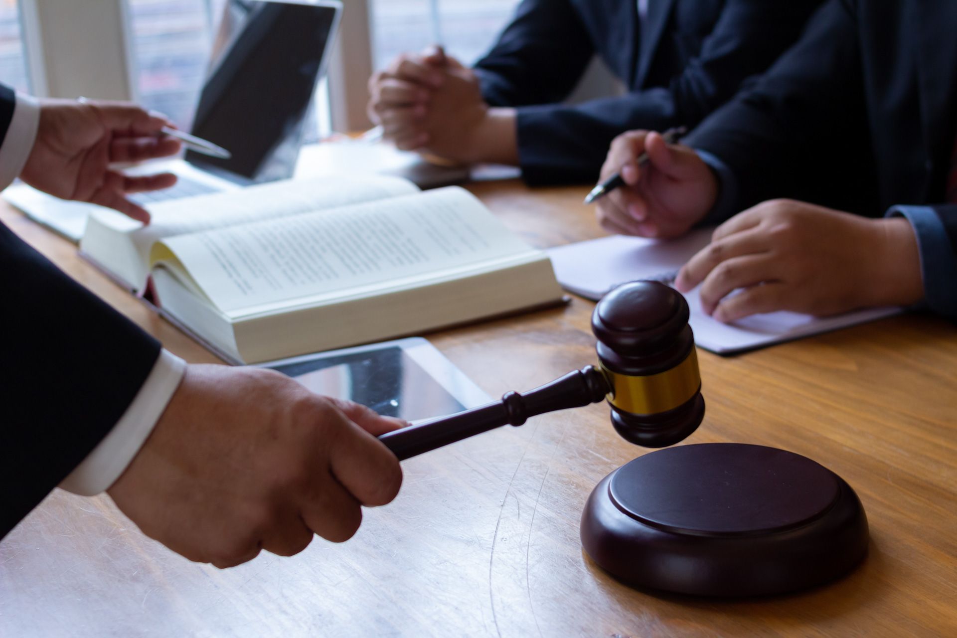 A judge is holding a gavel in front of a group of people sitting at a table