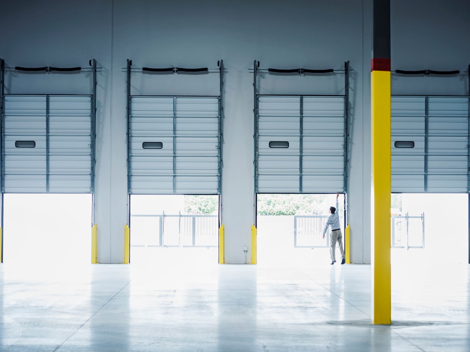 A man opens garage doors inside a warehouse.