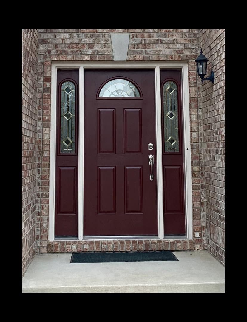 Maroon front door with sidelights set in a brick entryway