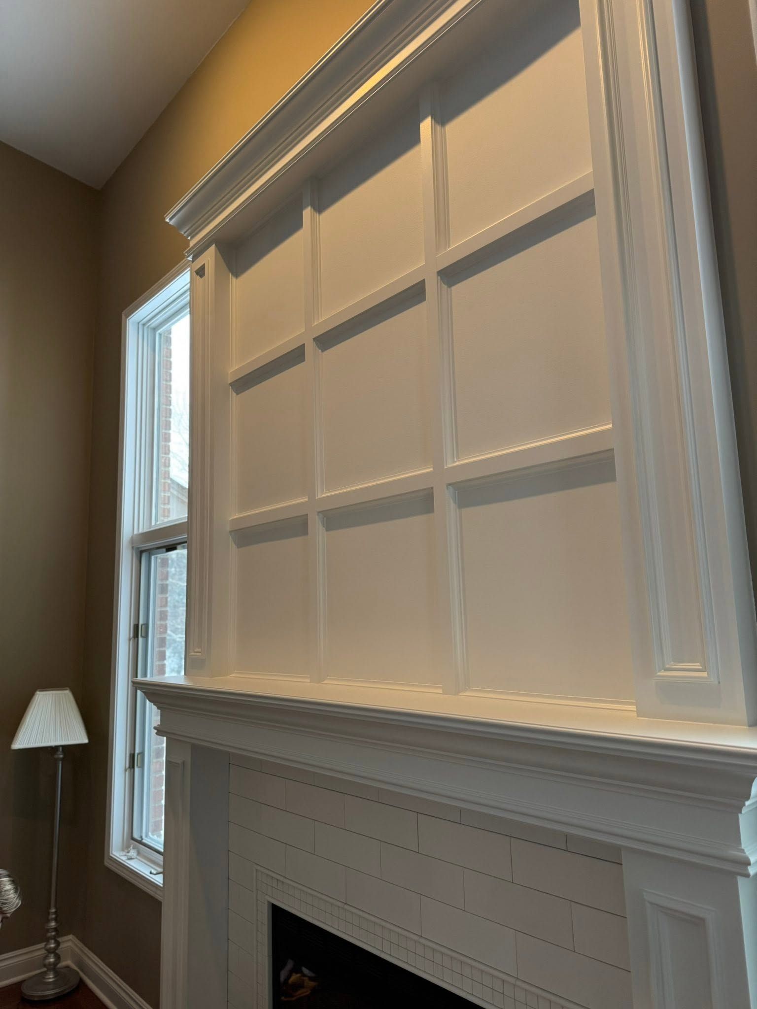 Living room fireplace with large white window blinds and a floor lamp beside a tall window