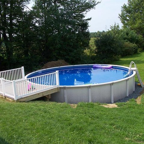 Above-ground backyard pool with white railing and blue water on a grassy lawn