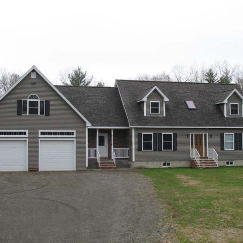 Two-story suburban duplex with attached garages, gray siding, and a driveway in front