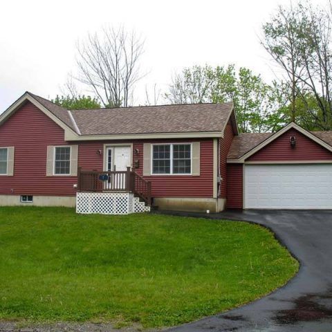 Red ranch house with white trim, attached garage, and curved driveway on a green lawn