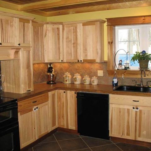 Wooden kitchen with black appliances, corner countertops, and a window over the sink.