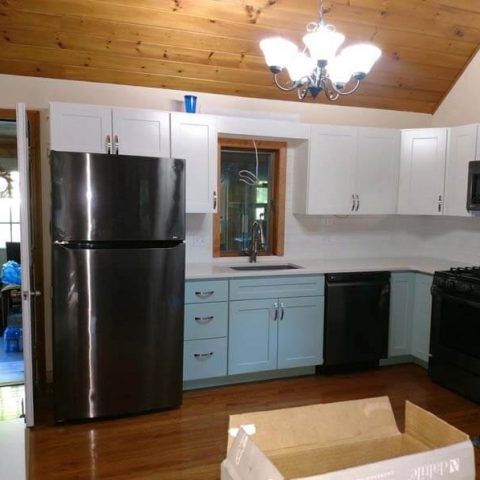 Kitchen with white cabinets, black appliances, blue lower cabinets, and a wood ceiling.