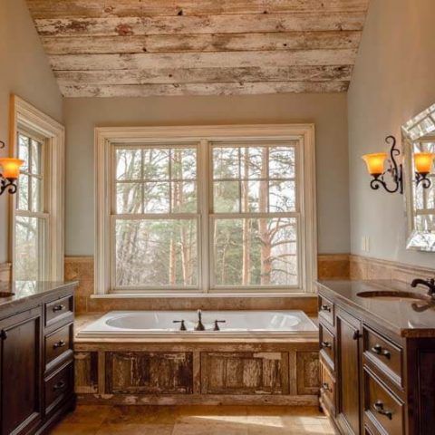 Rustic bathroom with a large window, soaking tub, and dark wood vanities